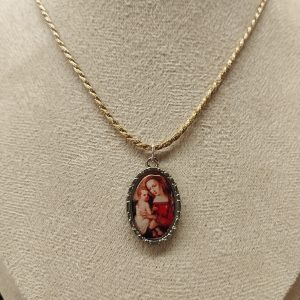 Medalla con dibujo de la virgen con niño entre sus brazos expuesto en maniquí