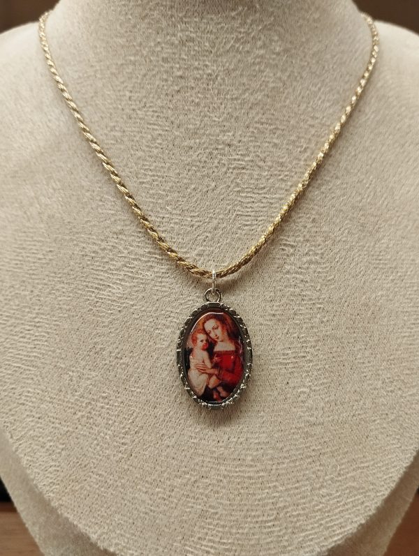 Medalla con dibujo de la virgen con niño entre sus brazos expuesto en maniquí